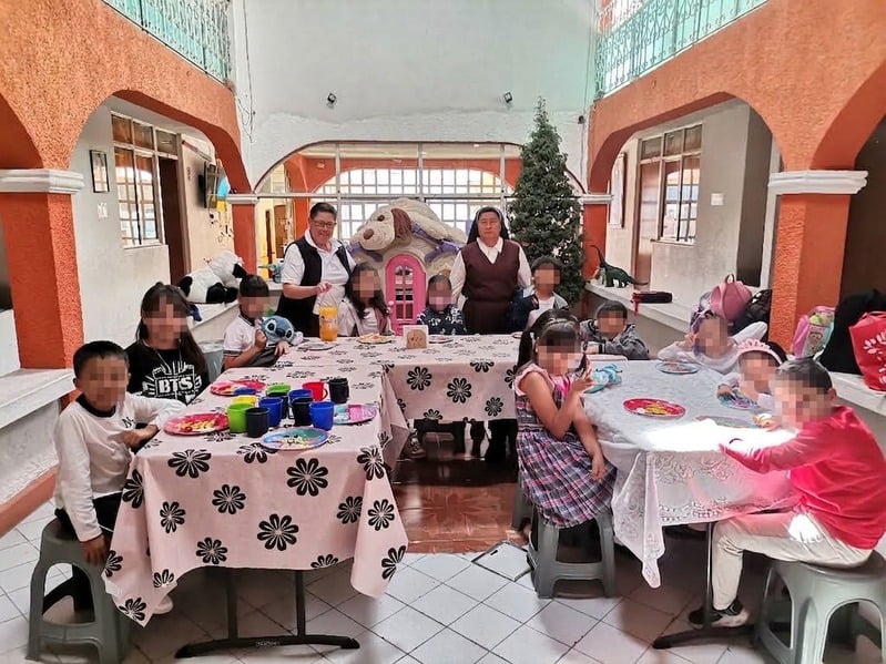 Hermana Terciaria Capuchina con niñas y niños en el patio